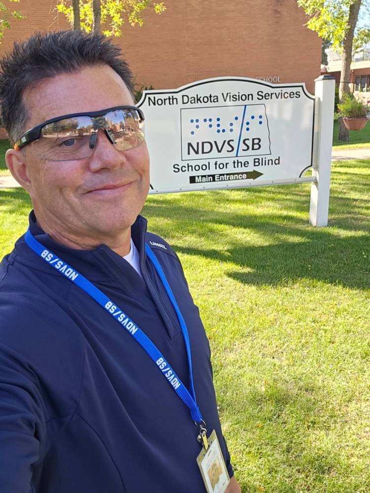 Chad in a selfie with the main entrance sign for NDVS/SB in the background.